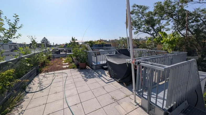 Geräumige Dachterrasse mit Fliesenboden, Pflanzen und weitem Blick über die Stadt.