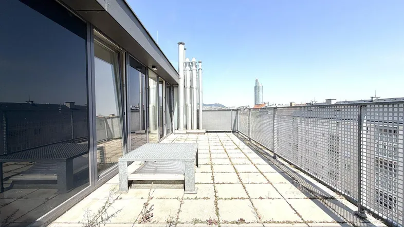 Geräumige Dachterrasse mit Stadtblick und Metalltisch, ideal für sonnige Tage.