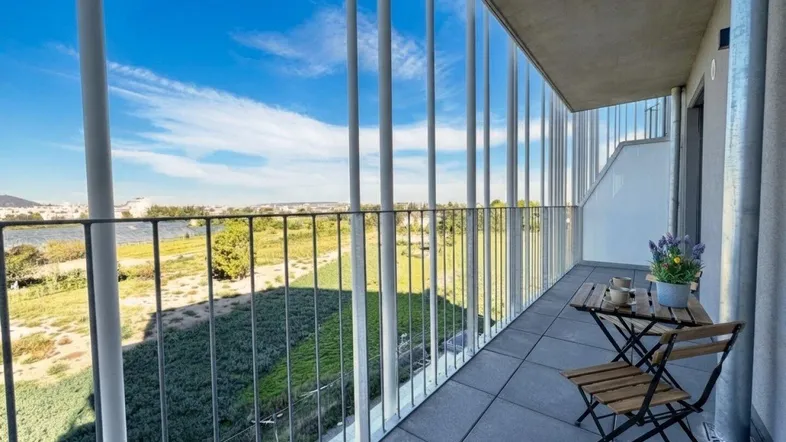 Moderner Balkon mit Sitzgelegenheiten und weitem Blick über grüne Felder und die Stadt.