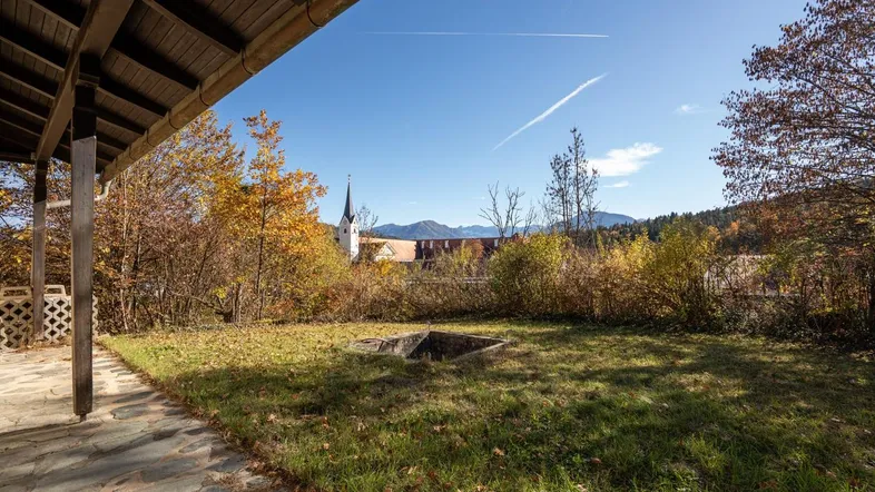 Überdachte Terrasse mit Steinboden und weitem Blick auf die Landschaft und Berge.
