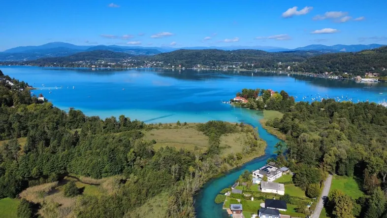 Panoramablick aus der Vogelperspektive auf einen See, Fluss und die umliegende grüne Landschaft mit Häusern.