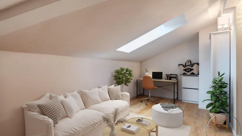 Gemütliches Wohnzimmer im Dachgeschoss mit Schrägdach, Sofa und Arbeitsbereich unter einem Dachfenster.