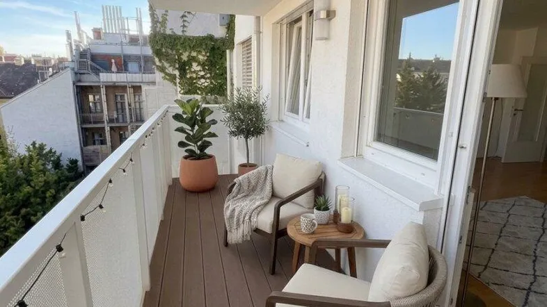 Gemütlicher Balkon mit Holzboden und Sitzgelegenheiten, ideal für entspannte Stunden im Freien.