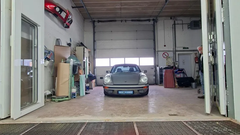 Große Werkstatt oder Garage mit einem klassischen Porsche, gesehen durch eine Bodenluke.