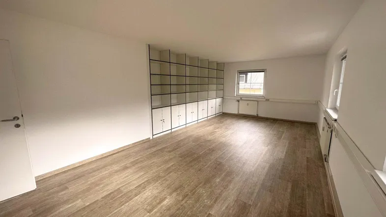 Geräumiger, heller Büroraum mit integrierten Regalen und Laminatboden, ideal für flexible Nutzung.
