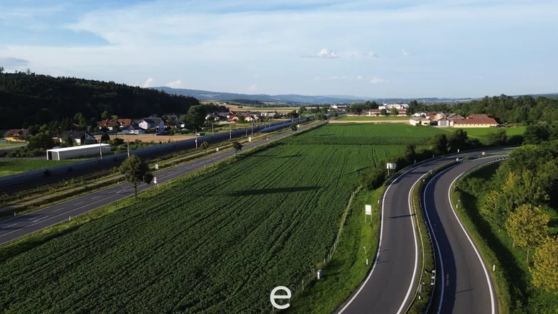 Luftaufnahme einer Autobahnkreuzung umgeben von grünen Feldern und ländlicher Bebauung unter blauem Himmel.