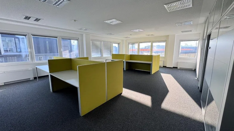 Heller und geräumiger Bürobereich mit modernen Arbeitsplätzen, großen Fenstern und Teppichboden, ideal für ein produktives Arbeitsumfeld.