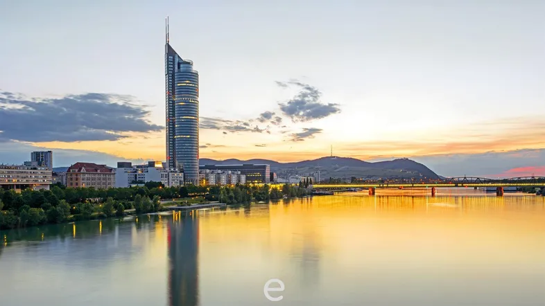 Panoramablick auf die Stadt bei Sonnenuntergang mit einem modernen Wolkenkratzer und einem Fluss.