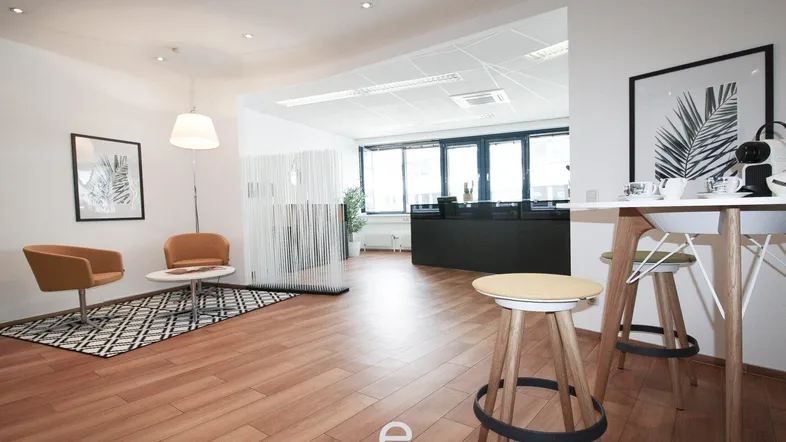 Moderner Empfangsbereich mit Wartezone, Holzboden und Blick auf den Arbeitsbereich.