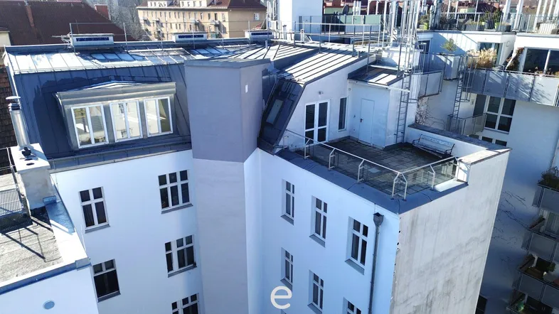 Dachterrasse mit Sitzbank und Blick auf die umliegenden Gebäude und Dächer der Stadt.