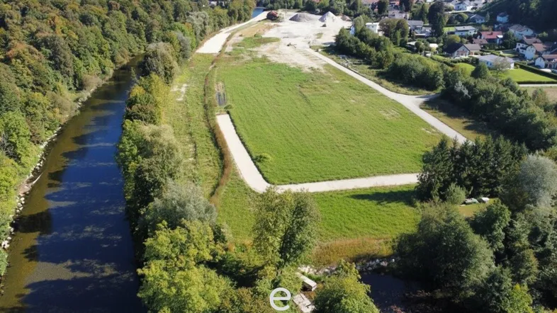 Luftaufnahme eines großen Grundstücks am Fluss mit Grünflächen und vorbereiteten Bauabschnitten.