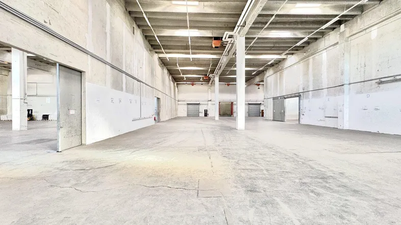 Geräumige, leere Lagerhalle mit hohen Decken und robustem Betonboden, bereit für industrielle Nutzung.