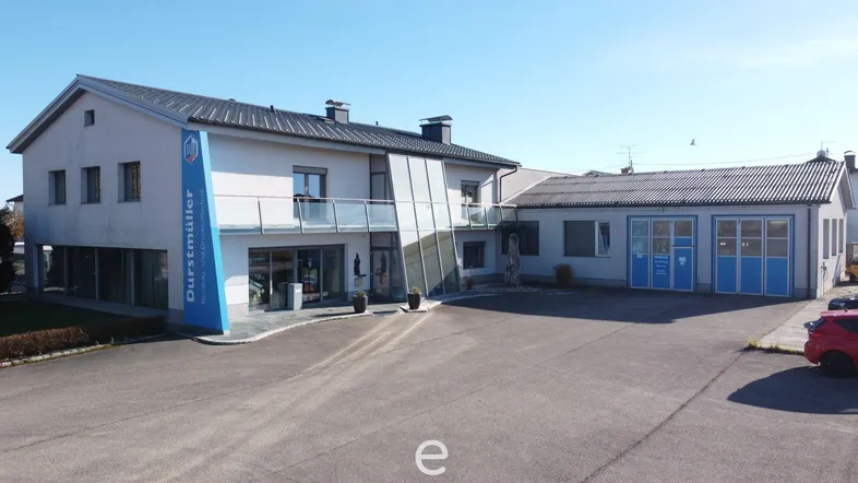 Gebäudeansicht eines modernen Geschäftsgebäudes mit großem Parkplatz und Glasfassade.