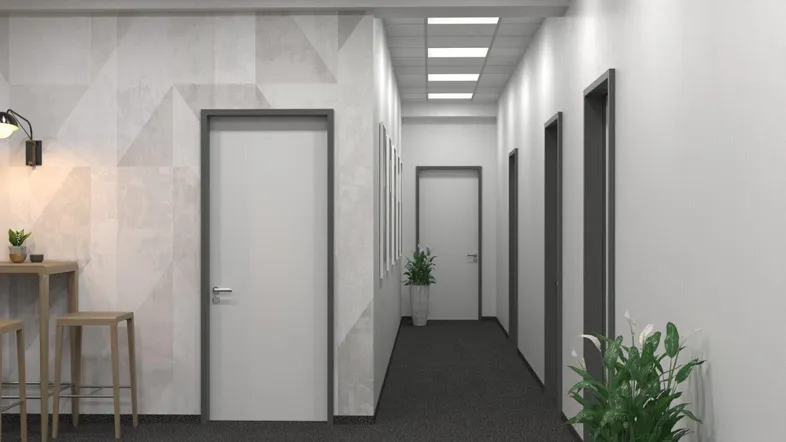Moderner Bürogang mit Teppichboden, weißen Wänden und mehreren Türen, beleuchtet durch Deckenleuchten.