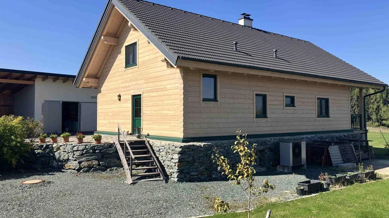 Rustikales Holzhaus mit Steinfundament und Satteldach unter blauem Himmel.