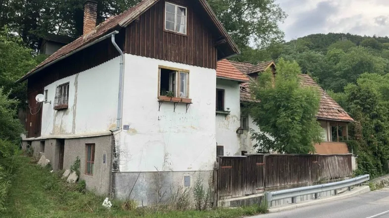 Altes Wohnhaus mit weißer Fassade, Holzelementen und Satteldach in ländlicher Umgebung.