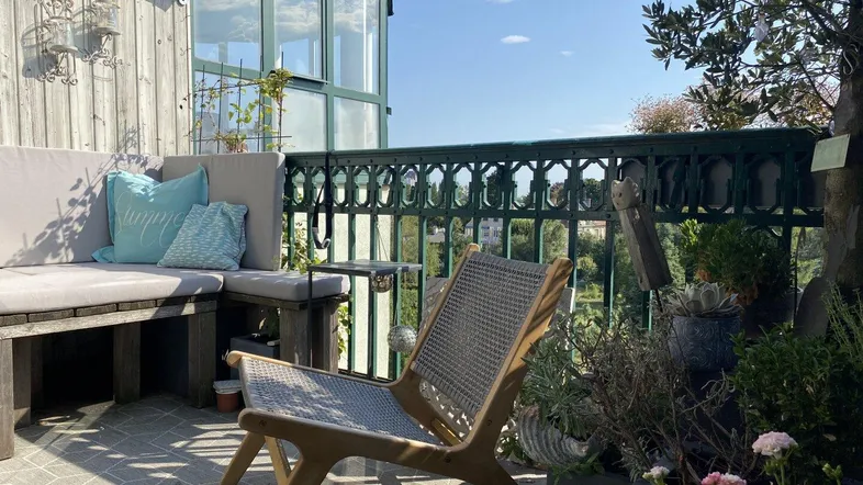 Gemütlicher Balkon mit Sitzgelegenheiten, vielen Pflanzen und Blick ins Grüne.