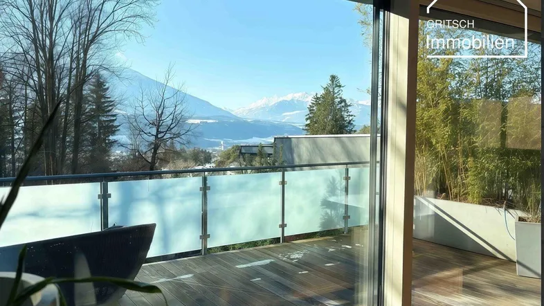 Heller Innenraum mit Zugang zu einer Holzterrasse und weitem Bergblick.