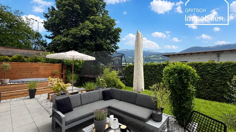 Geräumige Terrasse mit gemütlicher Lounge-Sitzgruppe, Sonnenschirm und Blick auf die umliegende Landschaft.