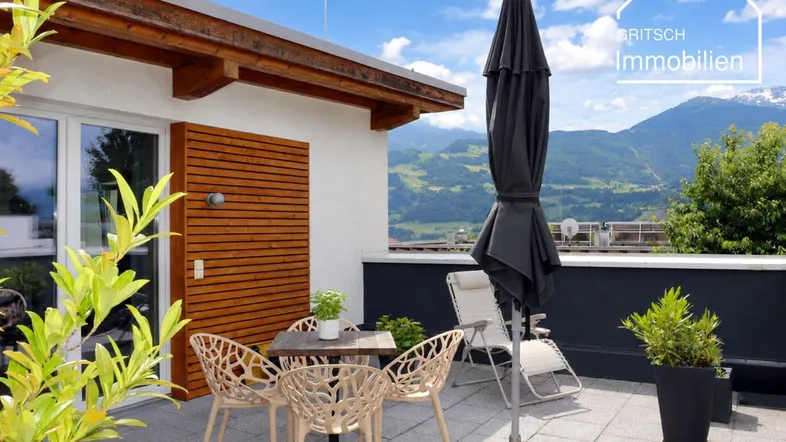 Geräumige Terrasse mit Sitzgelegenheiten, Sonnenschirm und herrlichem Bergblick.