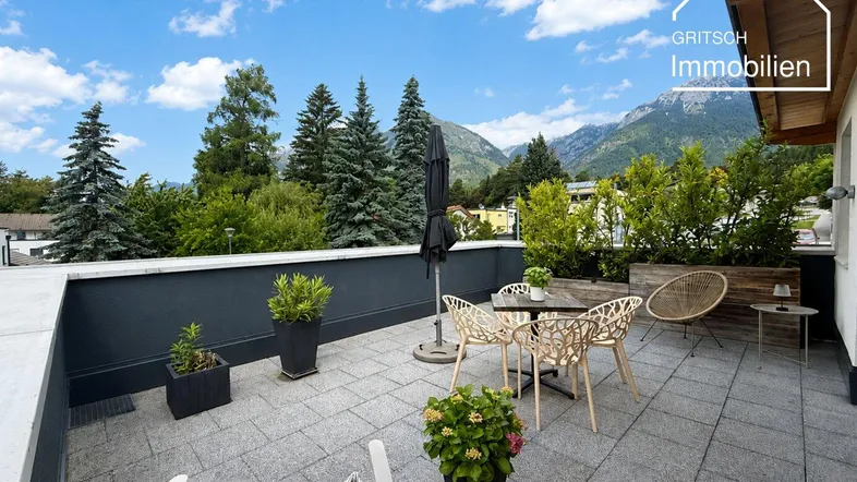 Geräumige Dachterrasse mit modernen Gartenmöbeln, Pflanzen und herrlichem Bergblick.