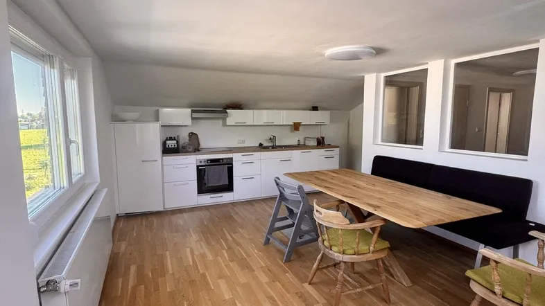 Helle offene Wohnküche mit Holzboden, Essbereich und Dachschrägen, ideal für Familien.