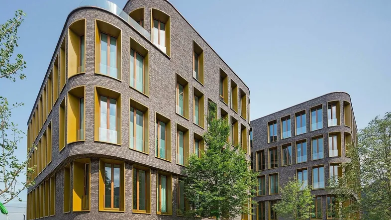 Moderne Wohngebäude mit geschwungenen Fassaden und großen Fenstern, umgeben von gepflegten Grünflächen.
