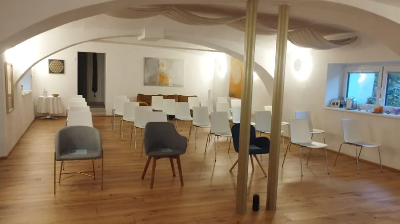 Heller Konferenzraum mit gewölbter Decke, Holzboden und modernen Stühlen, bereit für Veranstaltungen.