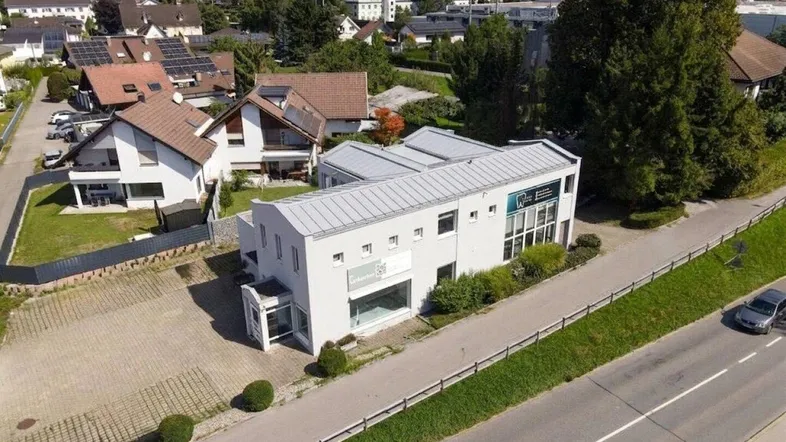 Weitläufige Luftaufnahme des modernen Gebäudes in einer Wohngegend mit weiteren Häusern und einer Straße.