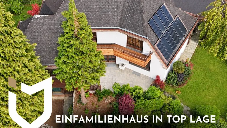 Luftaufnahme eines Einfamilienhauses mit großem Garten und Solarpaneelen auf dem Dach.