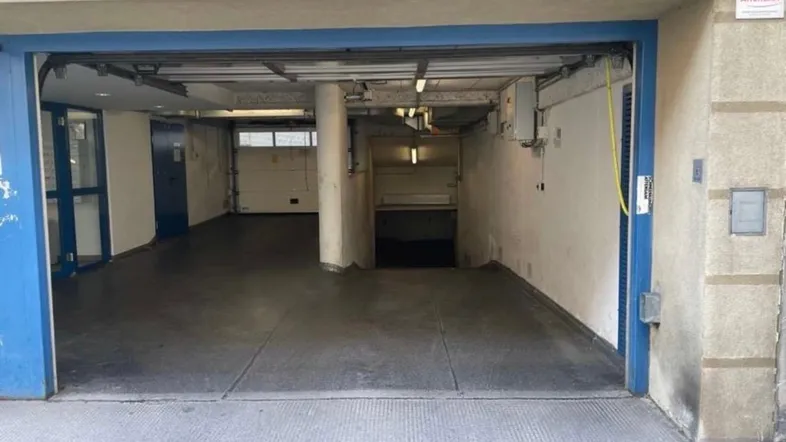Offene Einfahrt zu einer Tiefgarage mit mehreren Stellplätzen und Rolltoren.