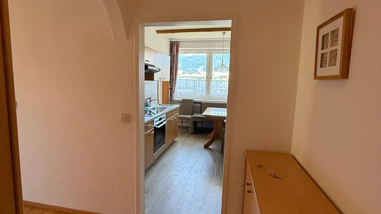 Heller Flur mit Holzfußboden und Blick in die Küche mit Essbereich und Bergblick.