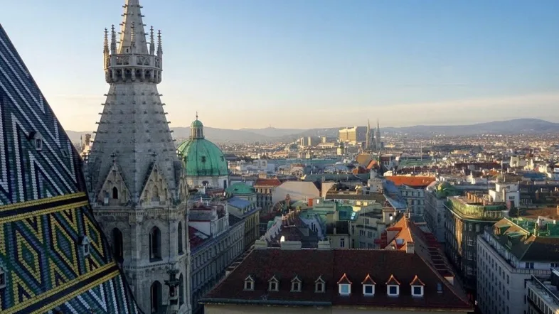 Panoramablick über eine historische Stadt mit Kirchturm und Dächern bei klarem Himmel.
