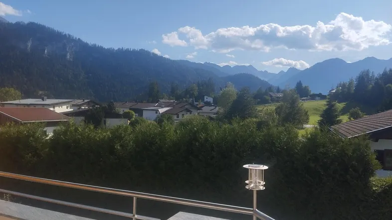 Panoramablick von einem Balkon auf die umliegende Berglandschaft und ein idyllisches Dorf.