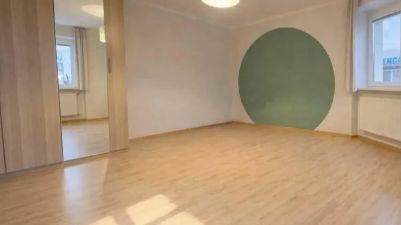 Helles Schlafzimmer mit modernem Laminatboden, einem großen Spiegelschrank und einer grünen Wanddekoration.