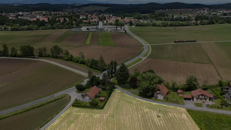 Weitläufige Luftaufnahme einer ländlichen Gegend mit Feldern, Straßen und einem Dorf in der Ferne.