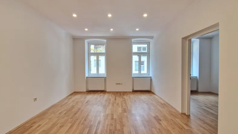 Helles Zimmer mit Parkettboden, weißen Wänden und Einbaustrahlern an der Decke.