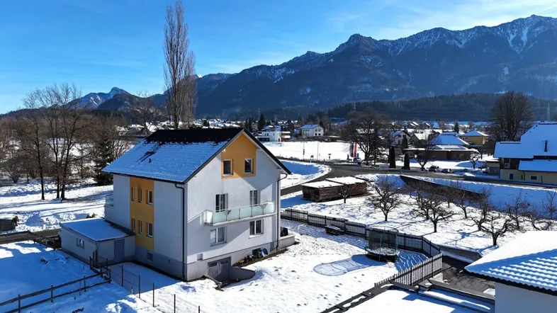Freistehendes Haus mit Balkon und Garten in verschneiter Landschaft mit Bergblick.