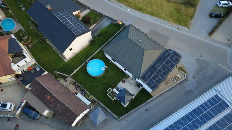 Luftaufnahme eines Hauses mit Garten, Aufstellpool, Pavillon und Solaranlagen auf dem Dach.