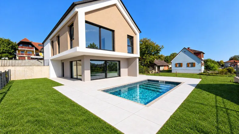 Moderne Villa mit privatem Pool und gepflegtem Rasen unter blauem Himmel.