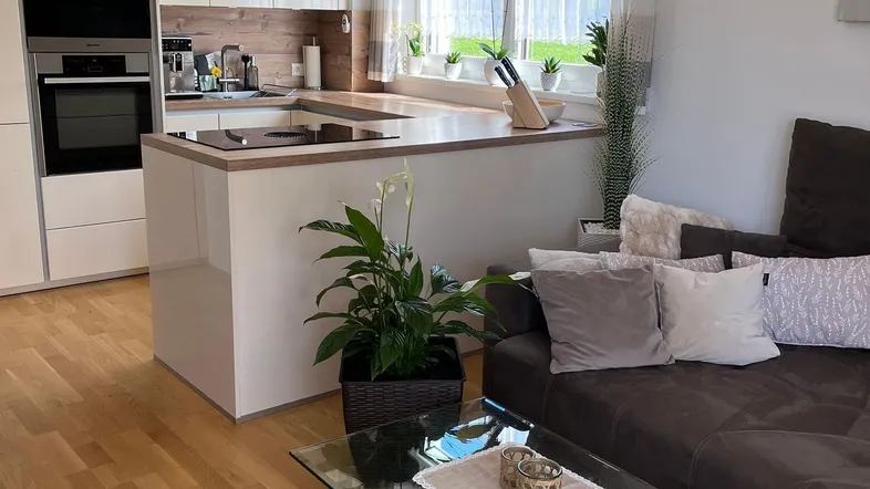 Helle, offene Wohnküche mit modernen Geräten, Holzboden und gemütlichem Sofa.