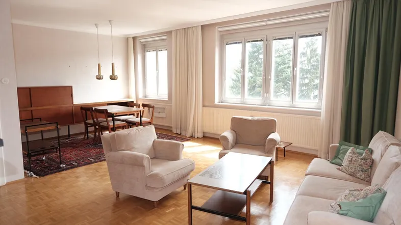 Helles Wohn- und Esszimmer mit Parkettboden, großen Fenstern und Blick ins Grüne.