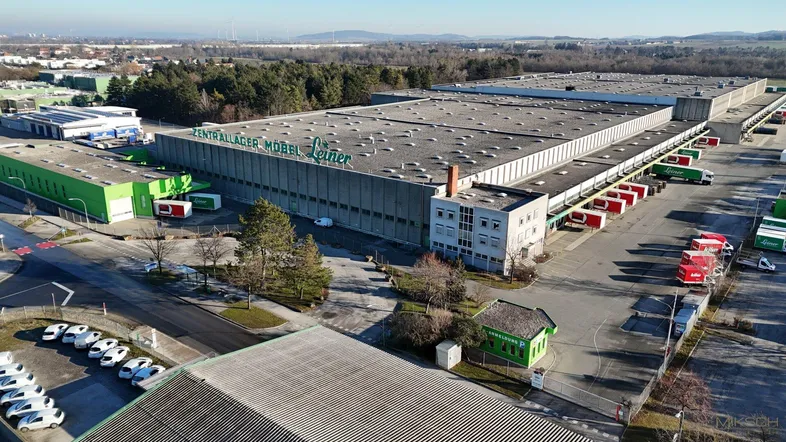 Luftaufnahme eines großen Logistikzentrums mit mehreren Gebäuden und Laderampen in einer Industriezone.