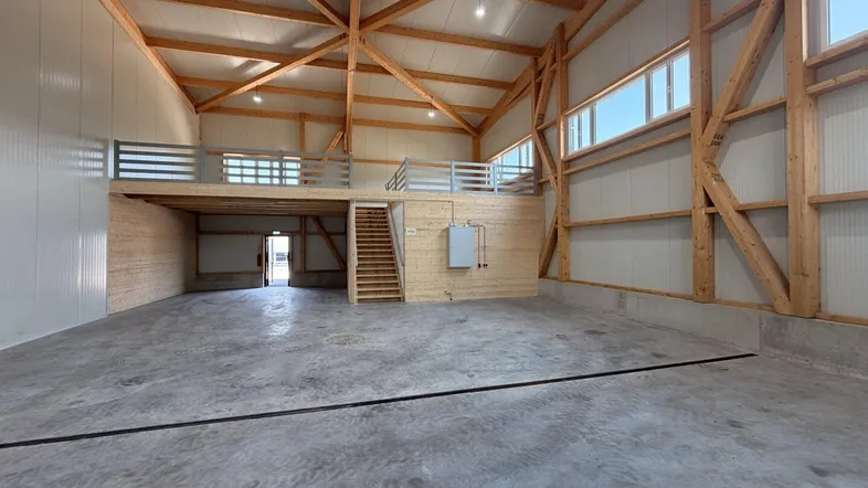 Geräumige Lagerhalle mit hohen Decken, sichtbaren Holzbalken und einer Holzempore.