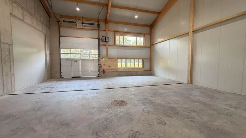 Geräumige, leere Lagerhalle mit hohen Decken, Betonboden und Sektionaltor, bereit zur Nutzung.