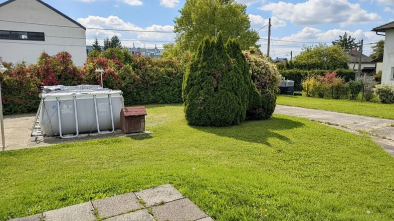 Großer Garten mit Rasenfläche, Hecken und einem Aufstellpool, ideal für sommerliche Entspannung.