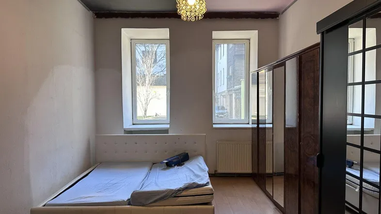 Schlafzimmer mit Doppelbett, großem Spiegelschrank und zwei Fenstern für natürliches Licht.