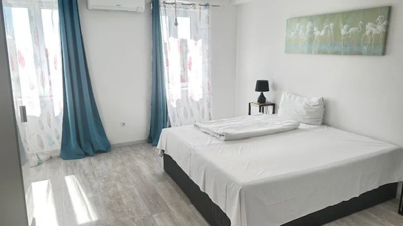 Helles Schlafzimmer mit Doppelbett, Klimaanlage und Zugang zu französischen Fenstern.