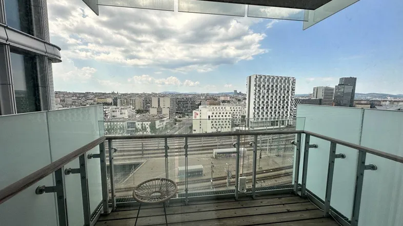 Balkon mit Holzboden und Glasgeländer bietet weiten Blick über die Stadt und Bahngleise.