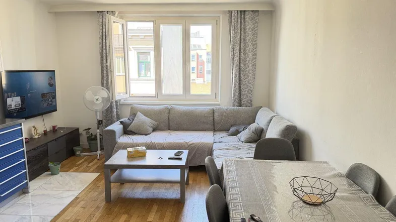 Heller Wohn- und Essbereich mit bequemer Couch, Esstisch und Blick nach draußen.